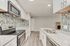 Chic modern kitchen with sleek white cabinets, elegant granite countertops, and stylish mosaic backsplash, offering a seamless look.
