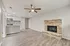 Modern living room with elegant wood floors, featuring a cozy brick fireplace and a stylish open kitchen with granite countertops.