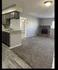 Inviting apartment interior with cozy carpeted living area, stylish brick fireplace, and modern kitchen cabinetry.