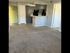 Inviting apartment interior with cozy carpeted floors, modern kitchen cabinetry, and a welcoming green door.