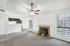 Inviting living room with plush carpet, cozy fireplace, and abundant natural light, open to modern kitchen.