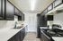 Sleek modern kitchen with black cabinets, stainless steel appliances, and elegant white countertops.