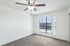 Bright room with plush carpet, large window, and modern ceiling fan, offering a serene view of the outdoors.
