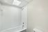 Bright and elegant bathroom featuring a pristine white bathtub and sleek shower fittings under a natural skylight.