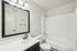 Bright and modern bathroom with sleek black fixtures, a spacious vanity, and a pristine bathtub, offering a refreshing and stylish retreat.