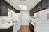 Modern kitchen with sleek black cabinets, white countertops, and elegant wood flooring.