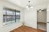 Bright apartment interior with wood flooring, large window with pool view, stylish chandelier, and entry to a carpeted room.