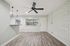 Modern living area featuring stylish brick accent wall, elegant wood flooring, and sleek ceiling fan, complemented by chic pendant lighting over open counter.