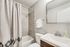 Elegant bathroom showcasing a modern vanity, sleek fixtures, and a contemporary shower with a tiled wall.