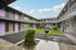 Charming apartment complex with modern design, featuring purple doors and a lush central courtyard, perfect for cozy living.