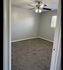 Inviting room with plush carpet flooring, soft gray walls, and a modern ceiling fan, perfect for relaxation.