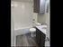 Contemporary bathroom with sleek gray cabinetry, modern fixtures, and a luxurious bathtub on elegant wood-look flooring.