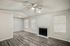 Elegant living room with modern gray flooring, ceiling fan, and a cozy fireplace, complemented by natural light from large windows.