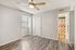 Bright and airy bedroom with elegant laminate flooring, modern ceiling fan, and colorful bathroom accents.