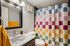Charming bathroom with a modern speckled countertop, vibrant checkered shower curtain, and an elegant framed mirror.