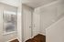 Inviting apartment entryway featuring sleek hardwood floors, contemporary white doors, and a bright window with stylish blinds.