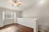Bright and inviting room with elegant hardwood floors, sleek gray walls, a stylish ceiling fan, and abundant natural light streaming through the window.