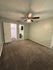 Bright and cozy bedroom with plush carpet, ceiling fan, and convenient walk-in closet access.