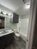 Modern bathroom with sleek dark cabinetry, stylish vanity, and pristine white bathtub highlighting a contemporary design.