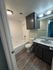 Modern bathroom featuring sleek cabinetry, elegant lighting, and a pristine bathtub, perfect for a refreshing retreat.