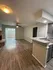 Inviting apartment interior with cozy carpeted floors, modern kitchen cabinetry, and a welcoming green door.