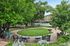 Lush garden setting with serene seating area, vibrant greenery, and charming outdoor ambiance near a residential community.