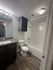 Modern bathroom with sleek granite countertop, elegant vanity lighting, and stylish wood flooring.