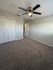 Bright, spacious bedroom with modern ceiling fan and plush carpet, offering ample natural light and closet storage.