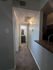 Inviting hallway leading to a modern bathroom, featuring sleek lighting and plush carpeting, showcasing both elegance and comfort.
