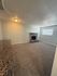 Inviting living room with cozy carpet, brick fireplace, and ample natural light, perfect for relaxation and gatherings.