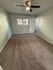 Inviting bedroom with fresh carpeting, a modern ceiling fan, and natural light from a broad window.