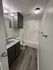 Modern bathroom featuring sleek gray cabinets, elegant tile flooring, and a pristine bathtub with stylish overhead lighting.