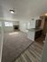 Inviting living space featuring a cozy carpet, charming fireplace, and a modern kitchen with sleek cabinets.