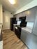 Modern kitchen with sleek gray cabinetry, black appliances, and elegant wood-style flooring.