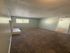 Inviting living room with plush carpet and abundant natural light streaming through a large window, perfect for cozy gatherings.