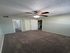 Inviting bedroom with plush carpet, modern ceiling fan, and ample natural light for a cozy ambiance.