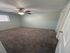 Bright and welcoming bedroom with plush carpet, ceiling fan, and ample natural light from a large window.