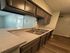 Modern kitchen with sleek brown cabinetry, elegant countertops, and double sink, offering a stylish and functional cooking space.