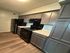 Modern kitchen with sleek black appliances, ample cabinetry, and chic wooden flooring.