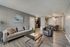 Modern open-concept living room with stylish grey tones, sleek furniture, and a cozy dining area adjacent to the kitchen.