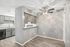 Modern kitchen and dining area featuring sleek gray cabinetry, granite countertops, a ceiling fan, and elegant lighting effects.