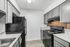 Modern kitchen with sleek gray cabinets, granite countertops, and energy-efficient black appliances.