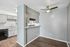 Chic apartment interior with an open kitchen featuring modern gray cabinetry, subway tile backsplash, and sleek ceiling fan in the dining area.