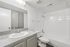 Bright and modern bathroom featuring a sleek granite countertop, pristine white bathtub, and elegant fixtures.