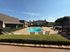 Inviting outdoor pool area with modern lounge chairs, surrounded by lush greenery under a clear blue sky.