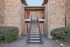 Charming apartment entrance with red doors, brick exterior, and well-maintained greenery, offering a welcoming and stylish vibe.