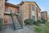 Charming brick apartment exterior with welcoming red doors and lush greenery, featuring easy stair access and modern design.