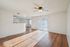 Bright and airy living space with elegant wood flooring, ceiling fan, and sliding glass doors leading to a sunlit outdoor area.