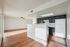 Bright open-plan kitchen and living area with elegant wood flooring, modern dark cabinets, and ample natural light.