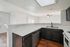 Modern kitchen with sleek dark cabinetry, wraparound countertops, and an inviting breakfast bar under bright lighting.